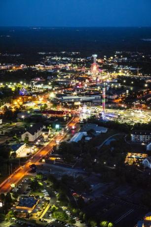 naktinis vaizdas iš Hwy 76, Branson Missouri su neoniniu apšviestu apžvalgos ratu, bokštu ir kt.