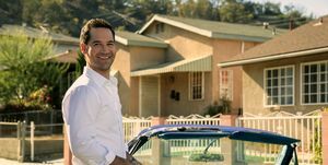 Manuel Garcia Rulfo kaip Mikis Halleris Linkolno advokatas 2 sezone šypsosi stovėdamas šalia vintažinio mėlyno Linkolno kabrioleto