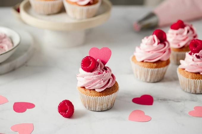 šviežiai pagaminti aviečių keksiukai ant virtuvės stalviršio skaniai atrodantys rožiniai keksiukai su aviečių ir popierinių širdelių užpilu