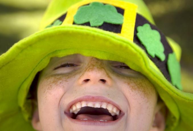 Iš arti besišypsančio strazdanoto vaiko šv. Patriko dieną, dėvinčio žalią spalvą su smėlinukais, kuriam reikia mielo antraštės