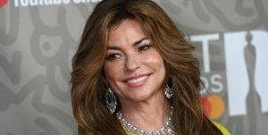 Shania Twain geltona suknele ir deimantų karoliais