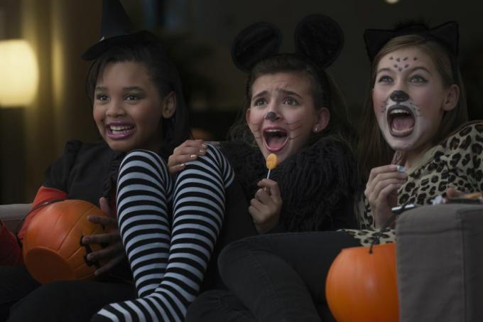 merginos su kostiumais kartu žiūri siaubo filmą Helovino proga