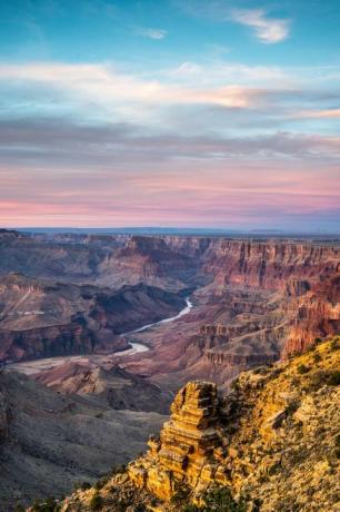 vaizdingas Grand Canyon nacionalinio parko vaizdas su saulėlydžiu fone ir per jį tekančia upe