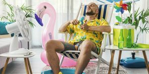 vyras, leidžiantis vasaros atostogas namuose, vėsina elektriniais ventiliatoriais ir sėdi ant šezlongo